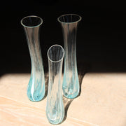 three tall and narrow clear glass vases with turquoise details at the bases by Cornish glass artist Helen Eastham