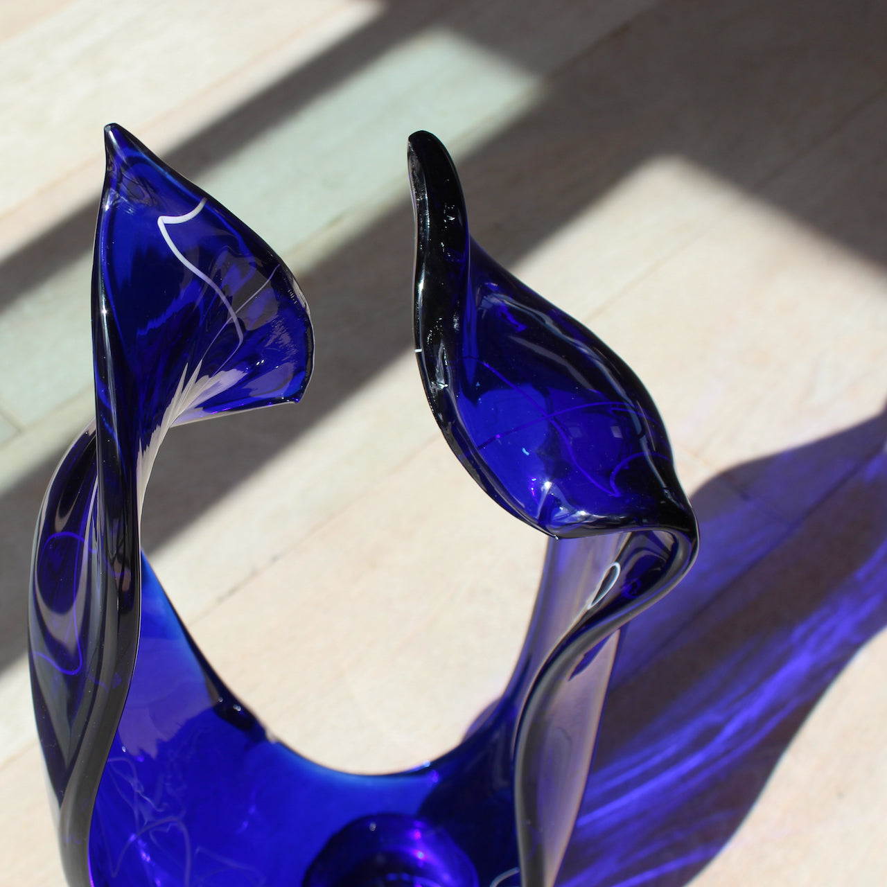 close up detail of the top of a tall blue glass sculpture with white detail by glass artist Benjamin Lintell