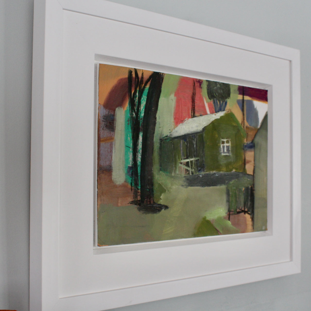 an oil painting in a white frame by Cornwall artist Heath Hearn of a green shed with a white roof in the clearing of some trees
