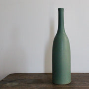green glazed ceramic bottle on a wooden table it's by UK ceramicist Lucy Burley
