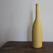 yellow ceramic bottle on a wooden table it's by UK ceramicist Lucy Burley