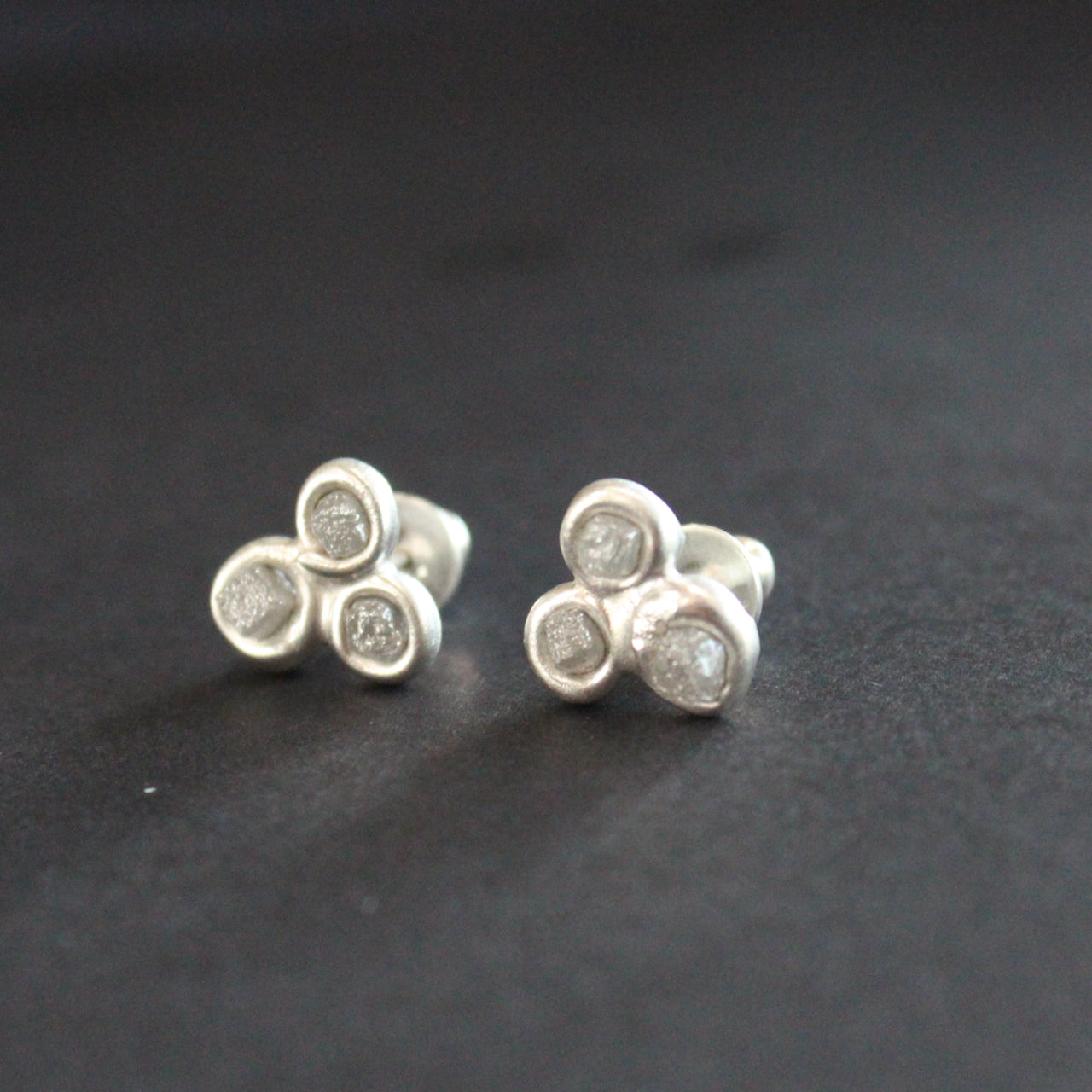 pair of silver and diamond stud earrings by Carin Lindberg each earring is made of three raw diamonds set in silver in a  triangular  formation