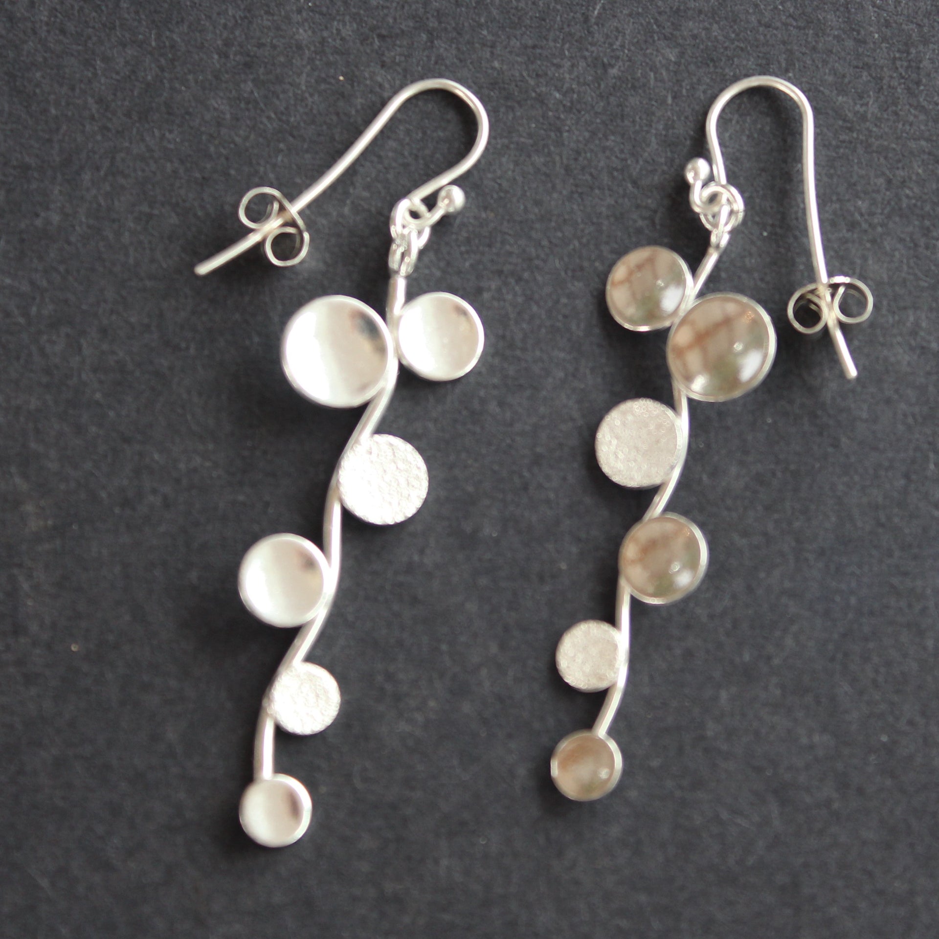 Long sliver earrings of small circles attached to central curved line made by Beverly Bartlett