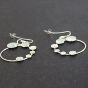 A pair of Round silver hoop earrings with small silver circles attached by Beverly Bartlett