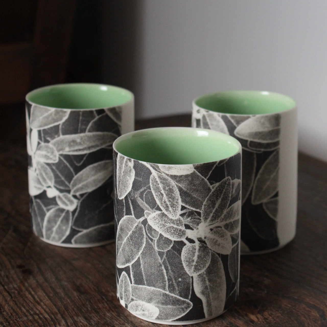 trio of small ceramic beakers by  UK ceramicist Heidi Harrington with a black and white photo image of leaves on the the exterior and green glazed interior