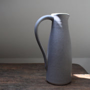 a soft grey coloured ceramic jug with handle by Lucy Burley on a wooden table in the sunlight