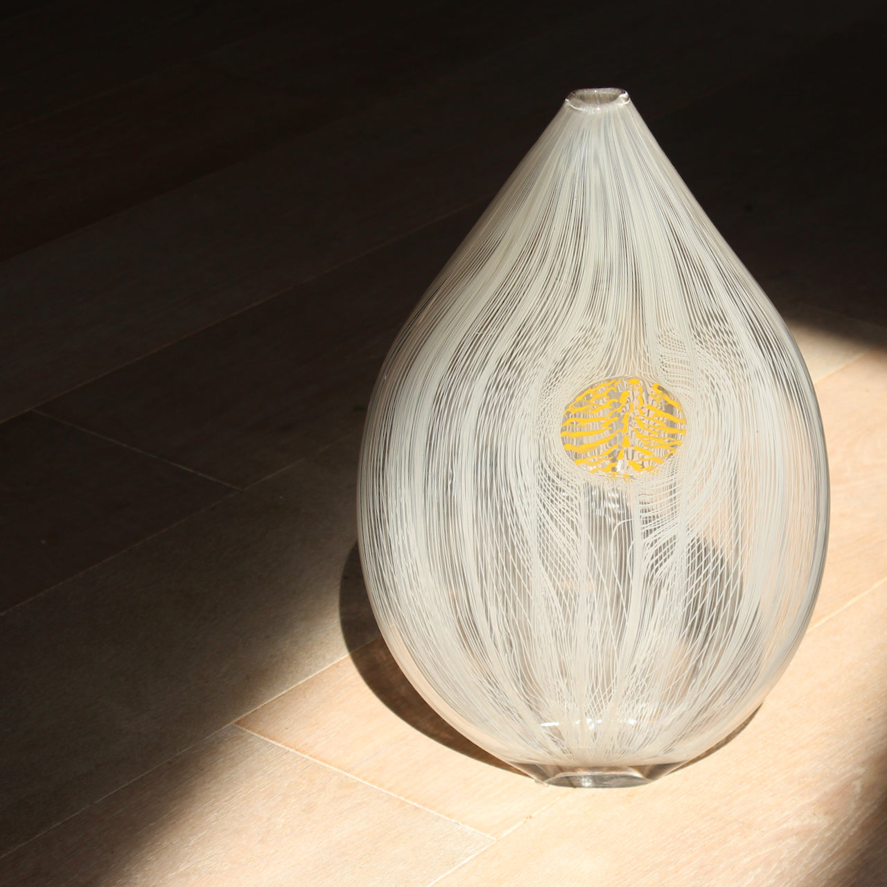 a Benjamin Lintell tear shaped glass vase in  white and clear with central yellow detail.