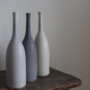 Trio of ceramic bottles in shades of grey on a wooden table  by potter Lucy Burley.