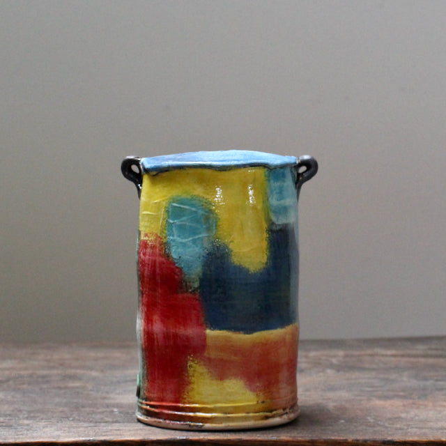 multi coloured ceramic vase with a tapered top and small lug handles by John Pollex, British potter.