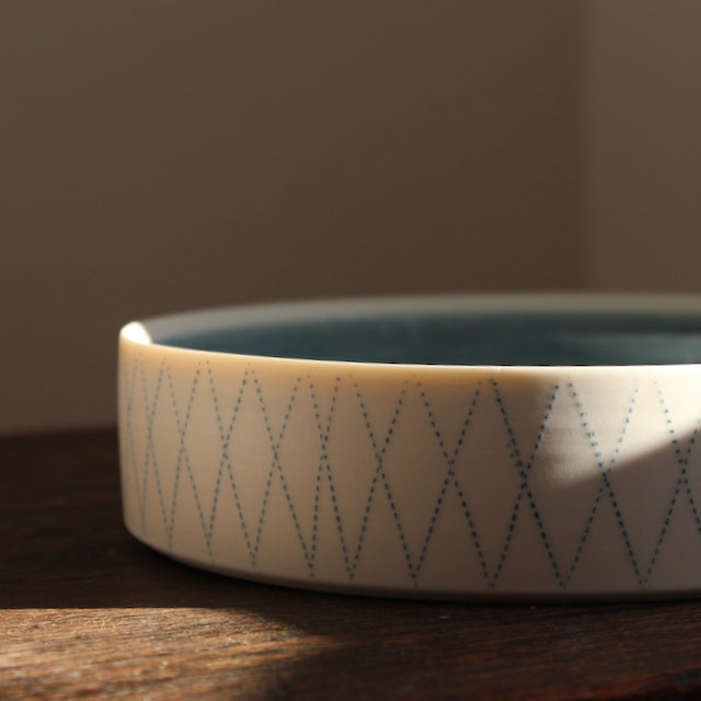 white porcelain serving dish with blue interior and blue diamond pattern on outside it's by Kathryn Sherriff of By the Line Pottery