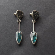 Long sliver earrings with a textured silver triangle falling to green oval shaped stones set in plain silver