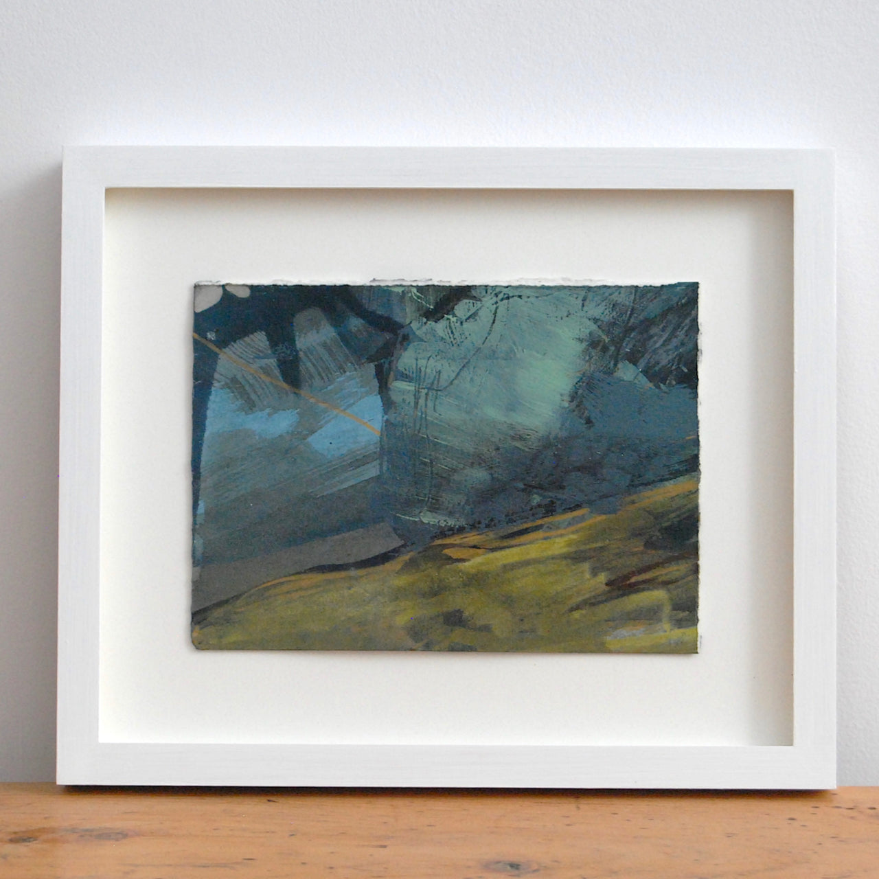 a framed  abstract painting by Alice Robinson-Carter of Rame Head peninsula in Cornwall, the landscape is dark mustard and the sky dark blues and black