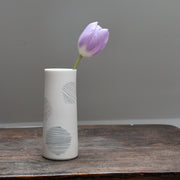 narrow ceramic white stem vase decorated with abstract circles with a lilac tulip in it