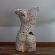 the rear view of a textured ceramic torso made by Pauline Lee standing on a wooden table