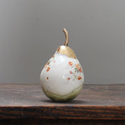 large ceramic white pear with orange floral detail and a gold stalk by Remon Jephcott. 