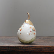 large ceramic white pear with orange floral detail and a gold stalk by Remon Jephcott.