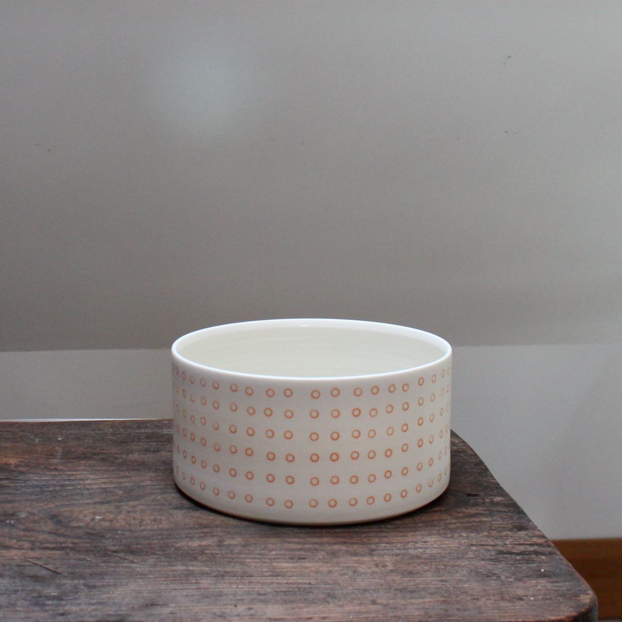 porcelain dish decorated with small orange circles on a wooden table