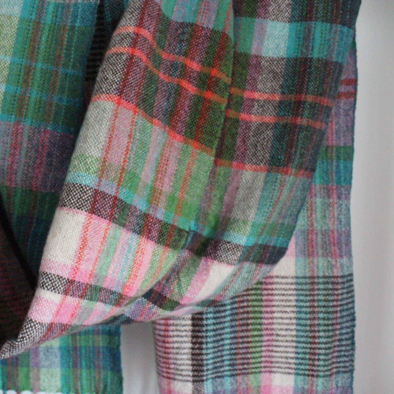 Detail of handwoven scarf in shades of pink, green and turquoise 
