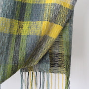 detail of textile designer Teresa Dunne's hand-woven fringed scarf in shades of blue, green and yellow