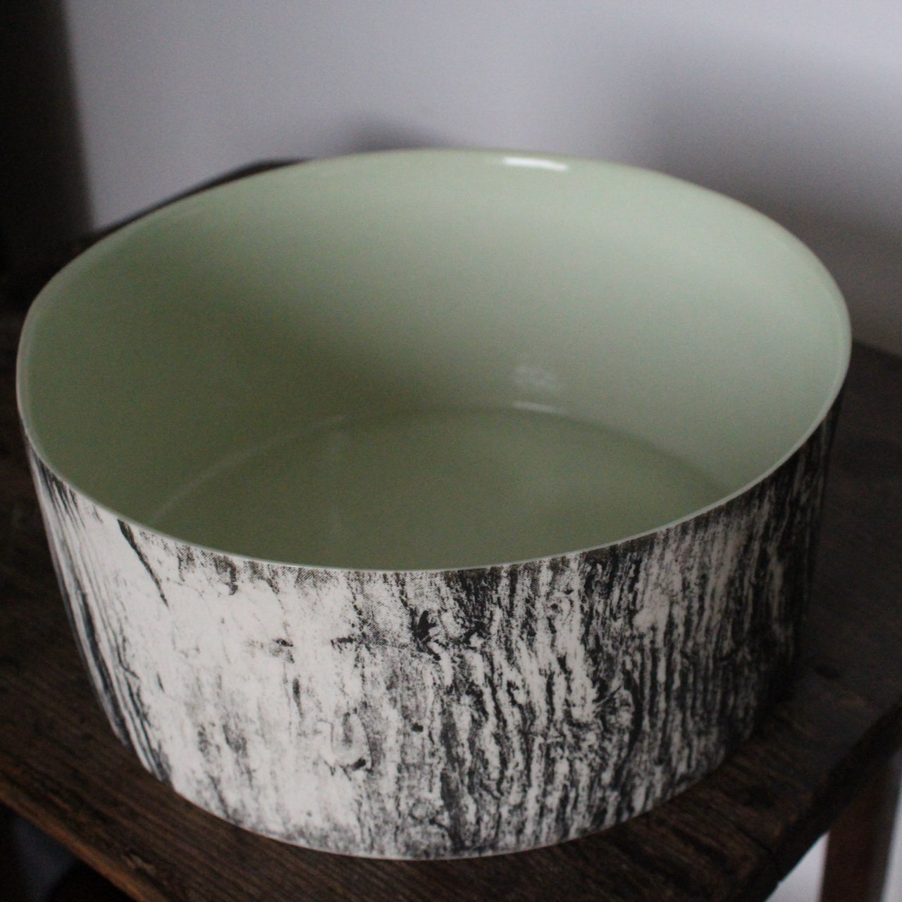 a round ceramic bowl with a green interior glaze and a black and white tree bark effect on exterior by UK ceramicist Heidi Harrington