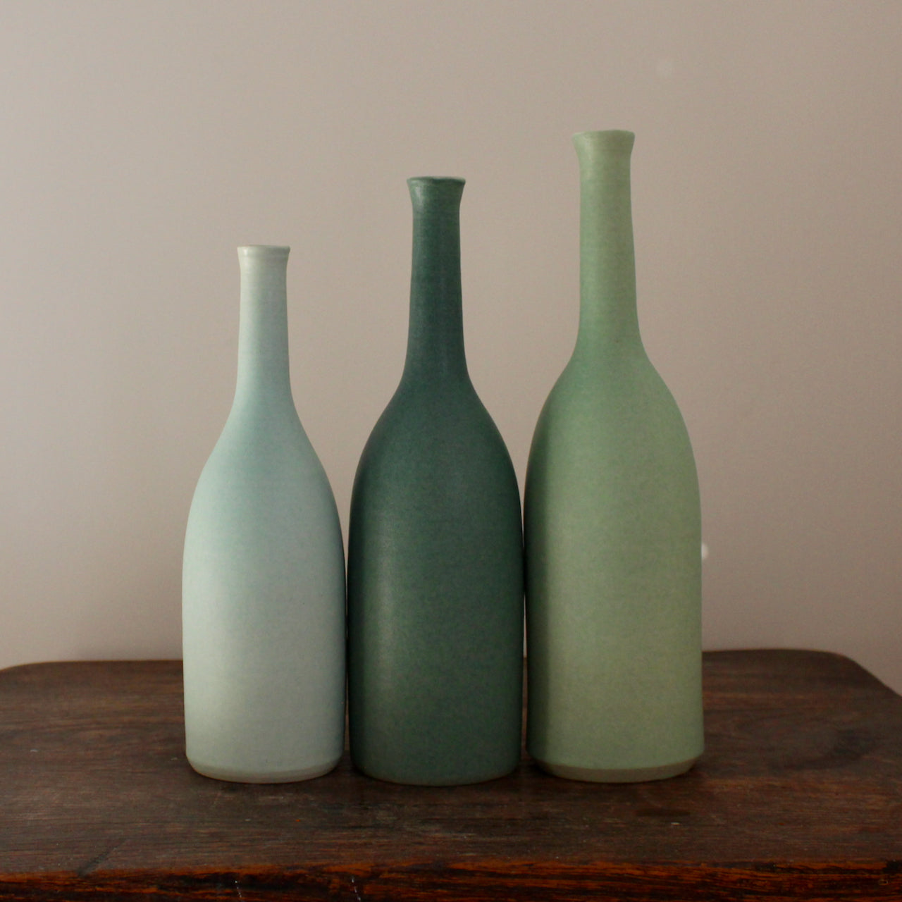 three ceramic bottles in different shades of turquoise and incremental sizes by UK ceramicist Lucy Burley