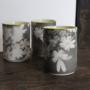 UK ceramicist Heidi Harrington trio of small ceramic beakers  with a black and white photo image of flower petals on the the exterior and pale yellow glazed interior
