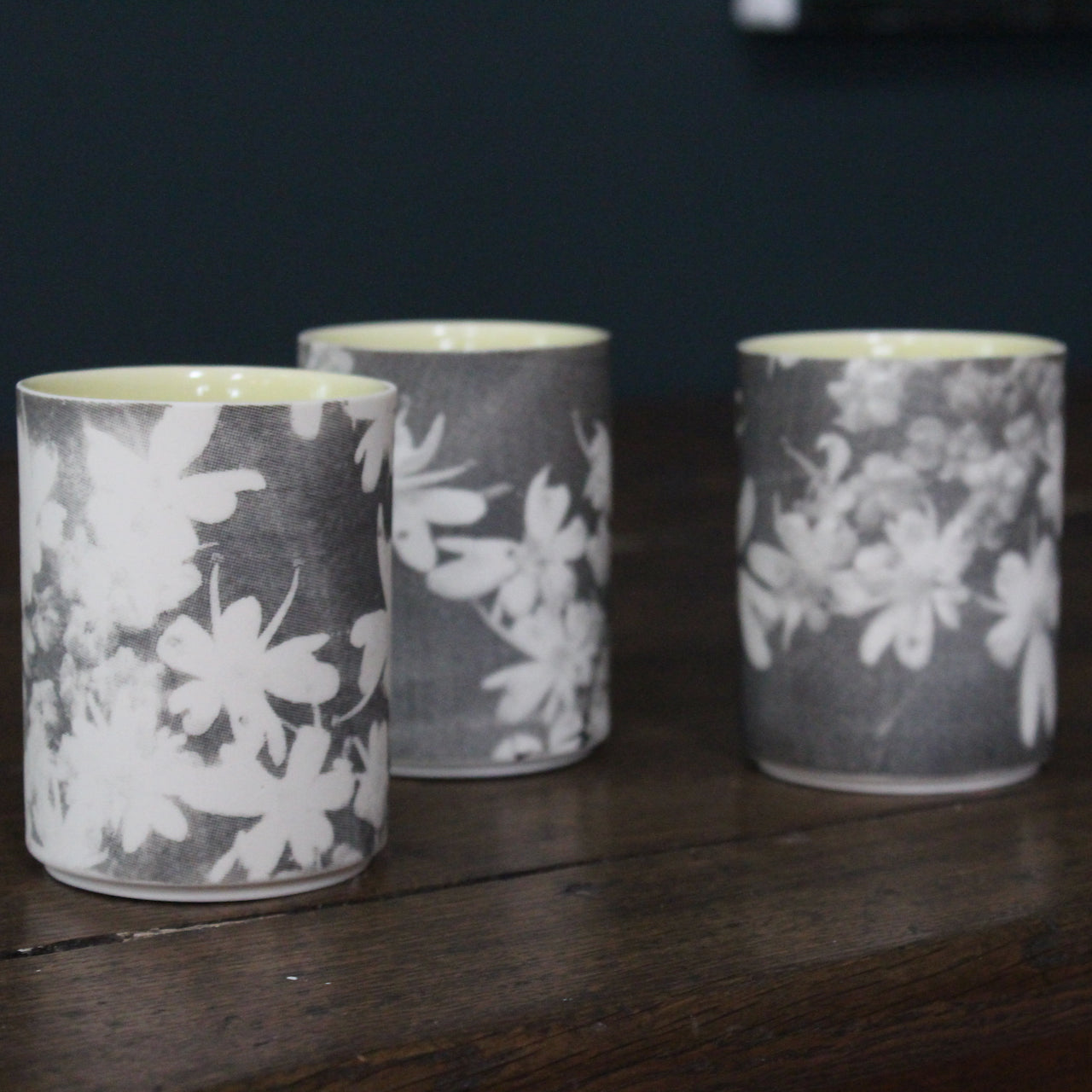 trio of small ceramic beakers by UK ceramicist Heidi Harrington with a black and white photo image of flower petals on the the exterior and pale yellow glazed interior 