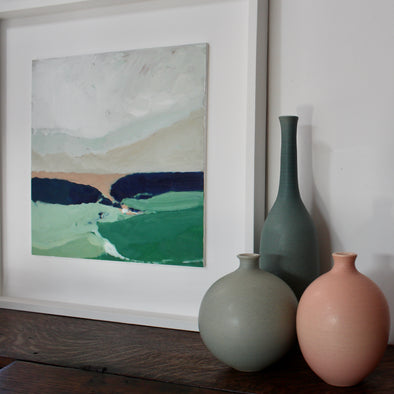 Three ceramic bottles next to a framed abstract painting of the countryside 
