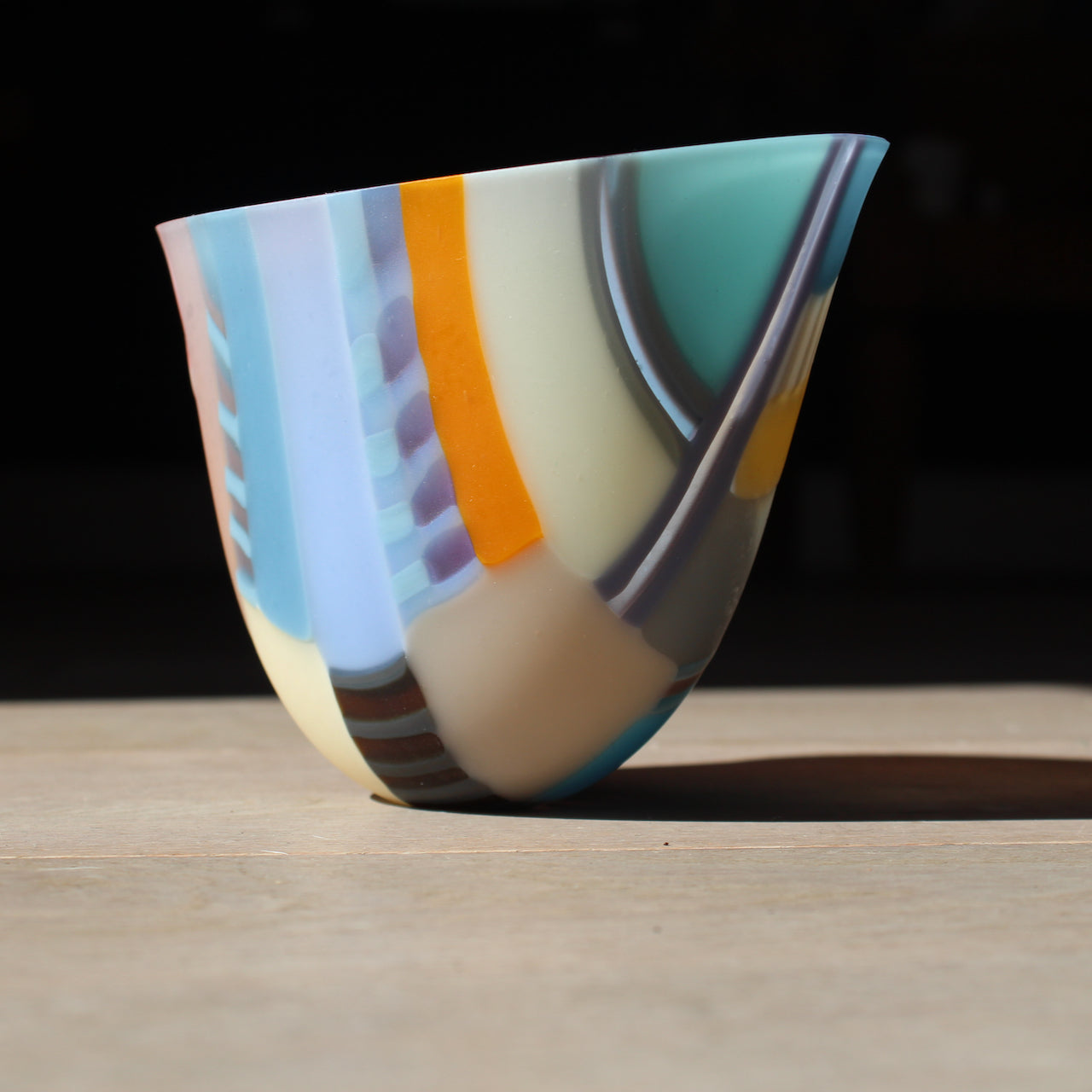 Round shaped bowl in vibrant tones of blue, orange, grey, pink by glass artist Ruth Shelley