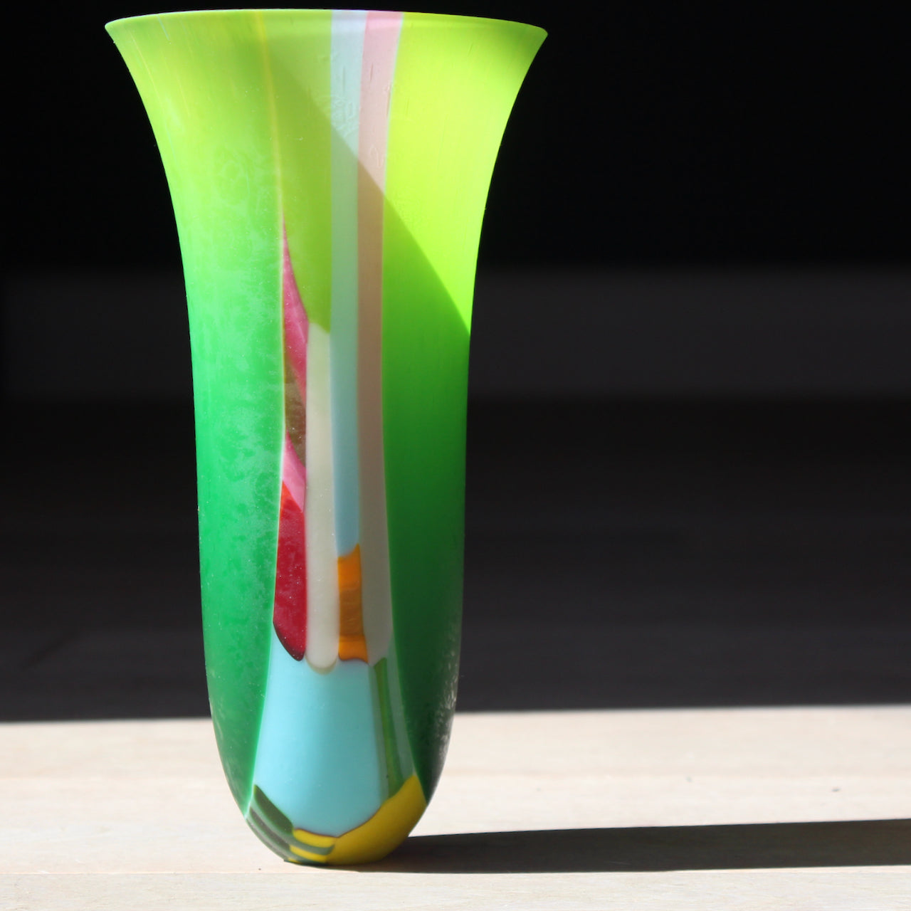 Tall vase by glass artist Ruth Shelley in vibrant tones of green, blue, pink, orange and yellow