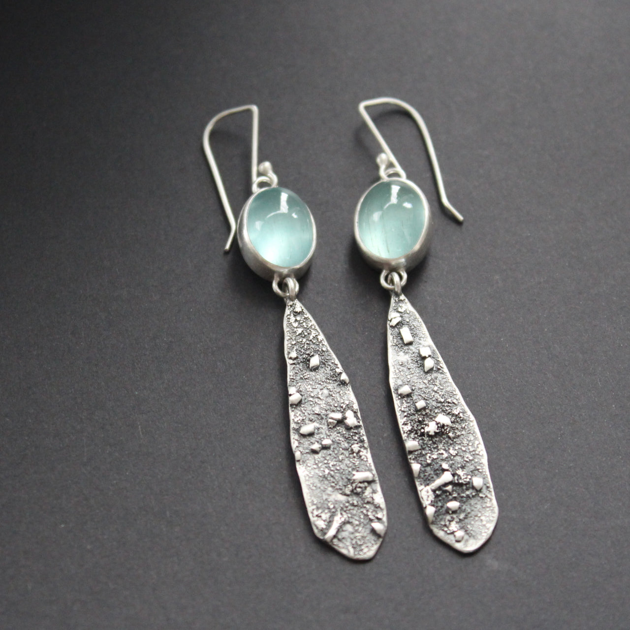 a pair of Carin Lindberg long lozenge shaped textured silver earrings with pale blue aquamarine stone setting 