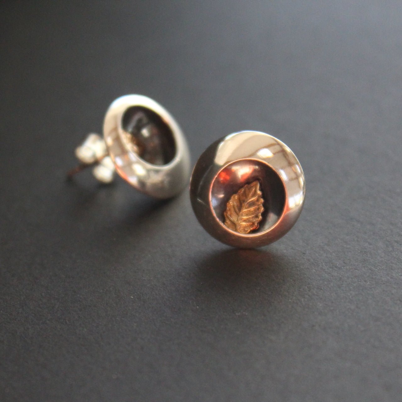 Round silver stud earrings with leaf inlay by artist Beverly Bartlett.