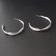 Organically hand sculpted silver Sea Siren hoop earrings, with delicate hand crafted surface detail and gold earring posts by Claire Stockings-Baker