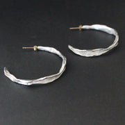 Organically hand sculpted silver Sea Siren hoop earrings, with delicate hand crafted surface detail and gold earring posts by Claire Stockings-Baker.