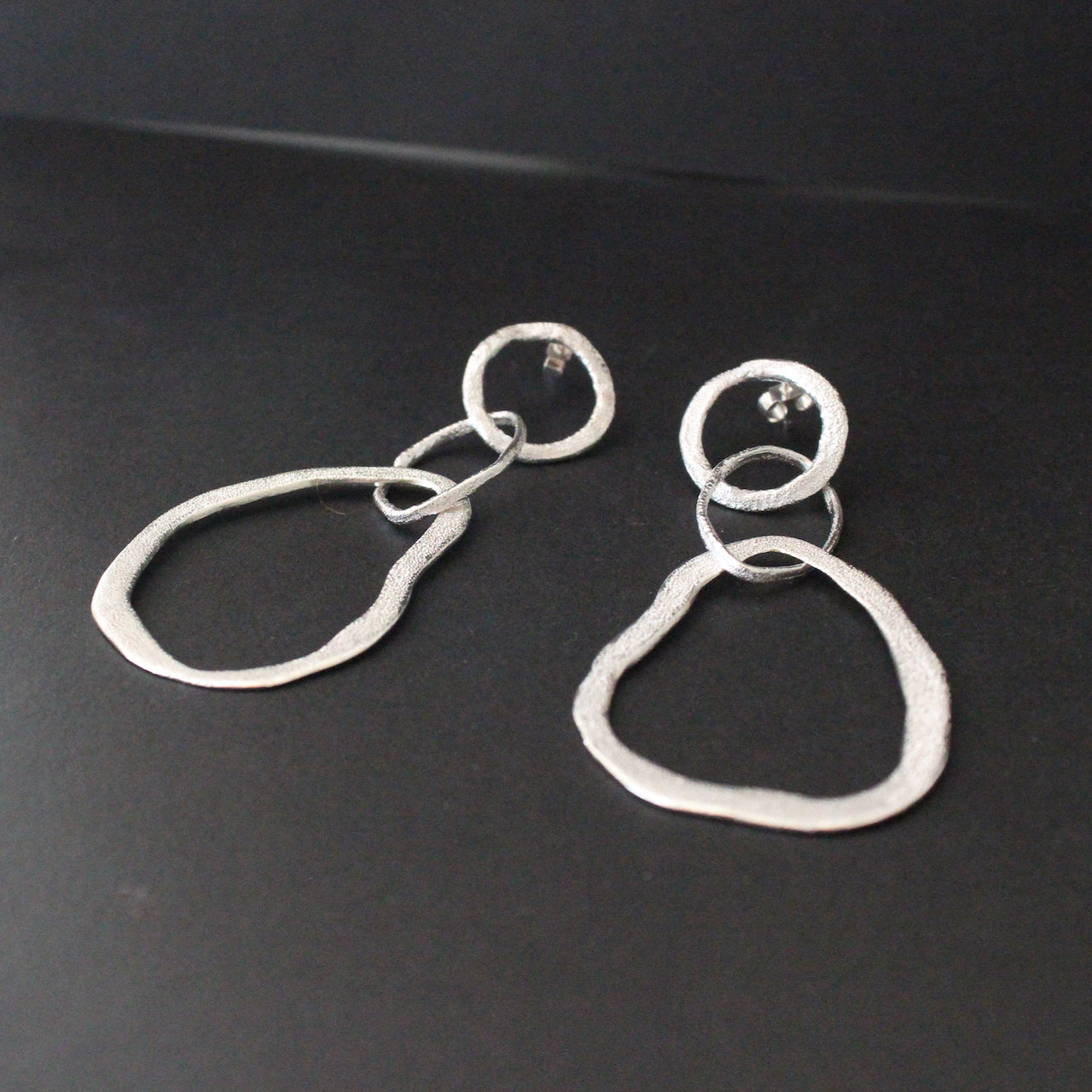 Organically sculpted silver drop earrings with delicate hand crafted surface design by Claire Stockings-Baker