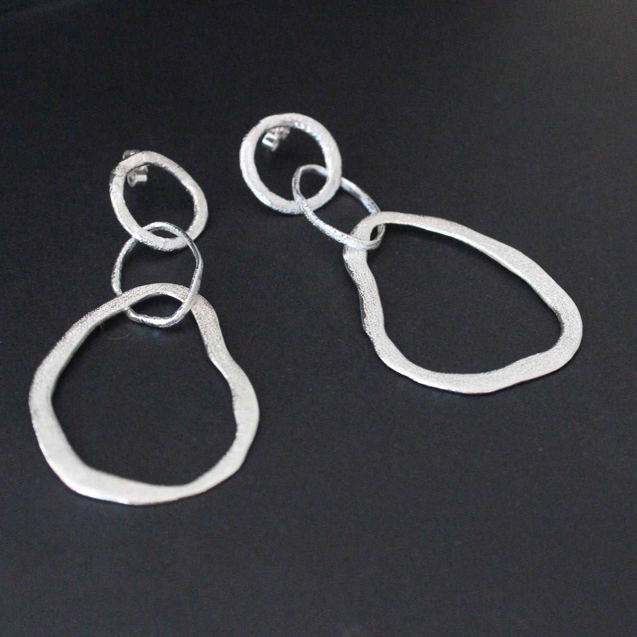 Organically sculpted silver drop earrings with delicate hand crafted surface design by Claire Stockings-Baker.