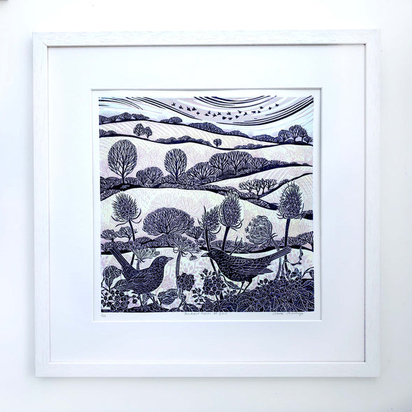 Framed lino print with blue and gold printed fields, trees and birds by artist Claire Armitage