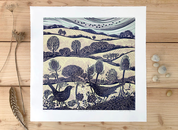 Lino print with blue and gold printed fields, trees and birds by artist Claire Armitage.