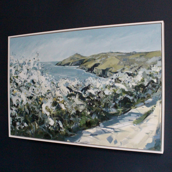 a framed painting of White blossom path with green coastline of Rame Head  in the background, blue sea, blue and white sky by Cornish artist Imogen Bone