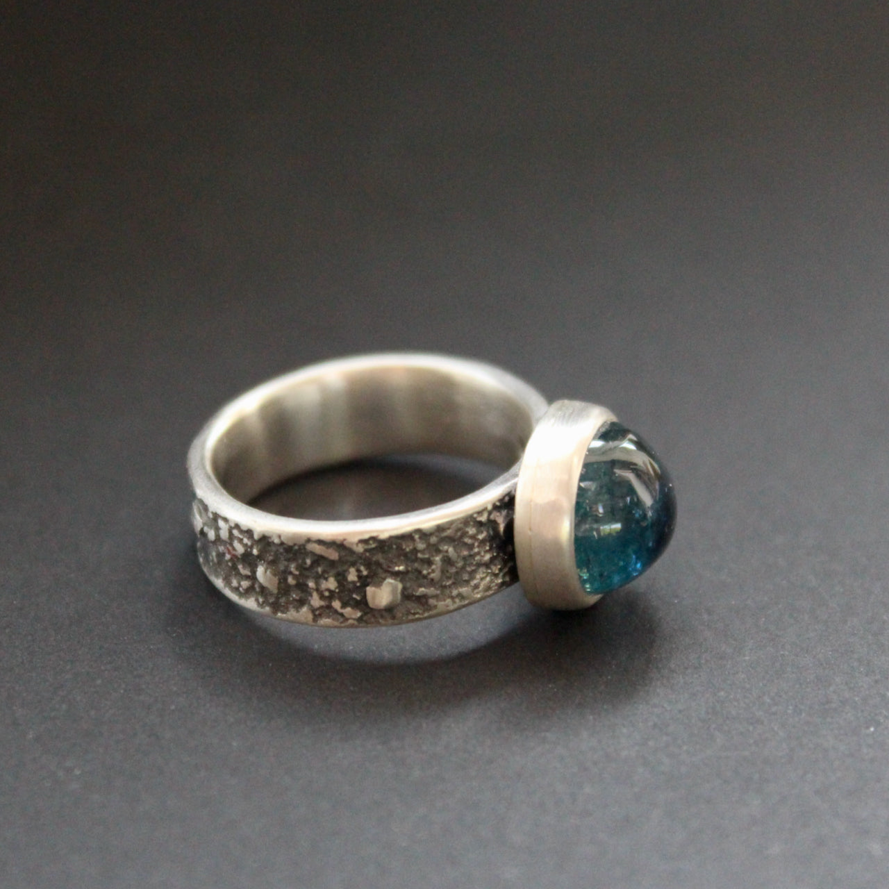 A Carin Lindberg textured silver ring with a round dark blue stone in a brushed silver setting 