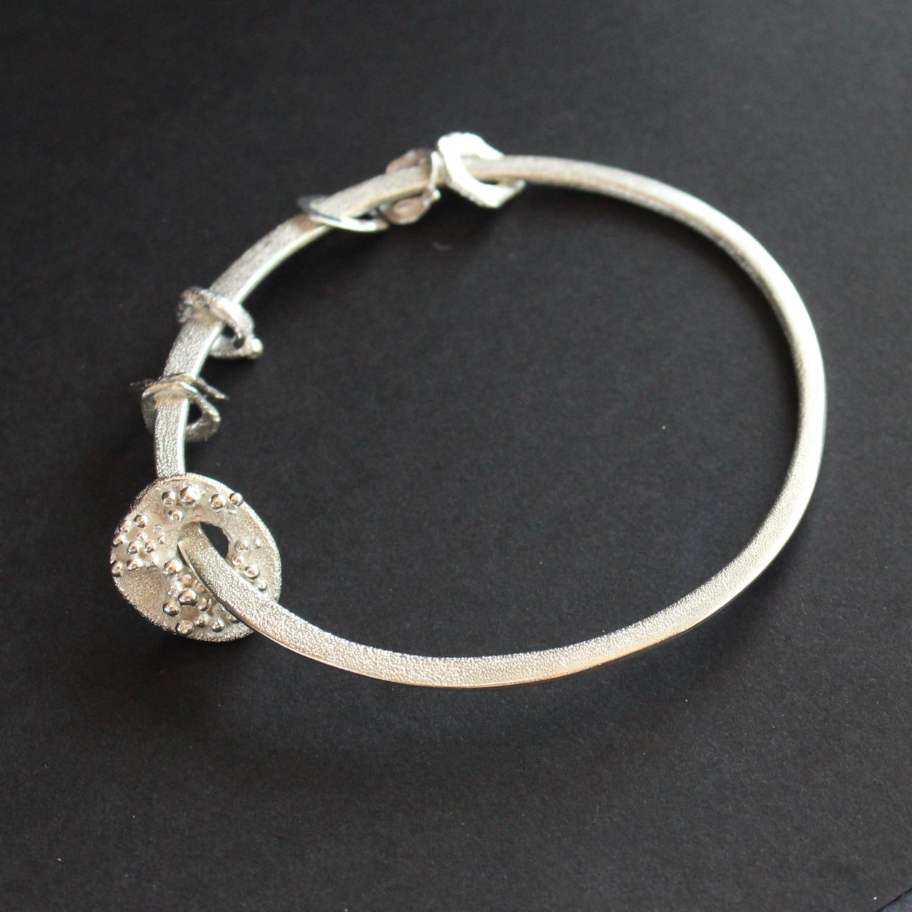 Silver bangle with silver discs of varying sizes on bangle by UK artist Claire Stockings Baker.