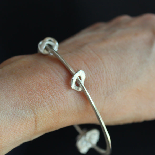 Silver bangle with silver discs of varying sizes on bangle by UK artist Claire Stockings Baker