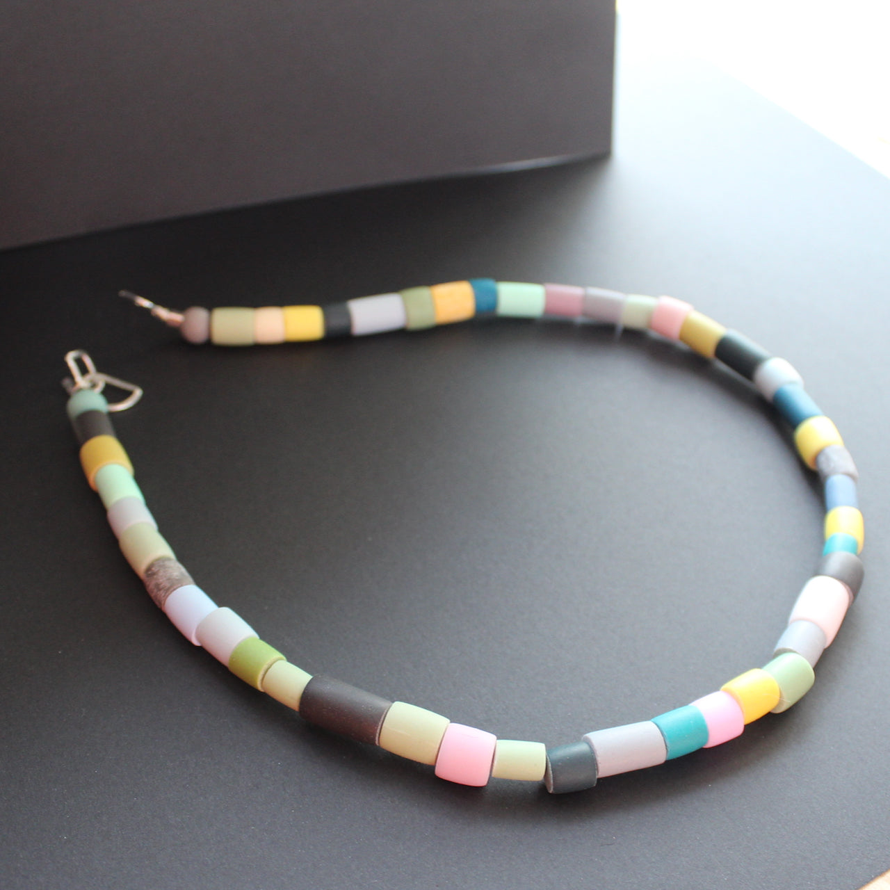 Tube bead polymer clay necklace in muted earth colours by artist Clare Lloyd.