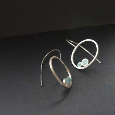 Round drop earrings with 2 dots of turquoise and aqua sitting inside the rings by artist Clare Lloyd