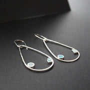 Raindrop shaped drop earrings with round and square dots in turquoise and aqua sitting inside raindrop by UK artist Clare Lloyd.