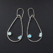 Raindrop shaped drop earrings with round and square dots in turquoise and aqua sitting inside raindrop by UK artist Clare Lloyd