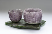 Heavily textured purple glass vessel sitting alongside larger purple vessel on glass slab by artist Caroline Reed