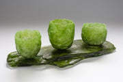 Set of three green textured vessels sitting on glass slab by Caroline Reed.