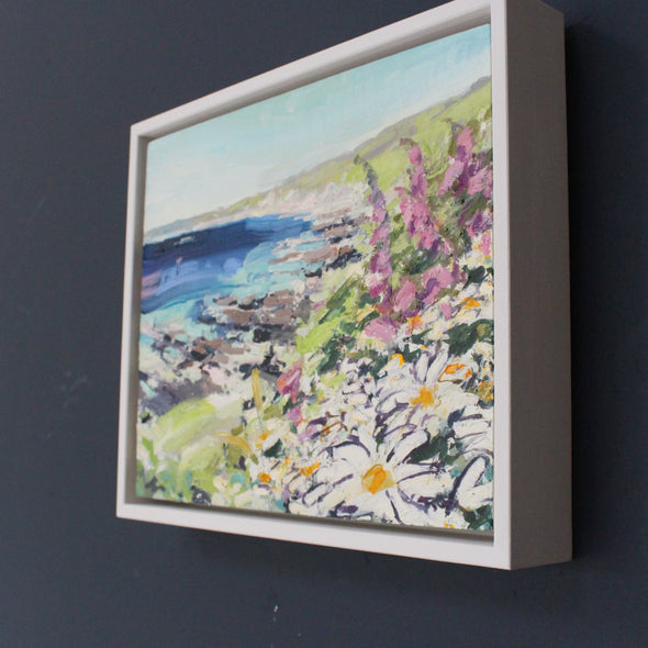 White and purple flowers in the foreground on headland with blue sea and grey rock formations by Cornwall artist Jill Hudson