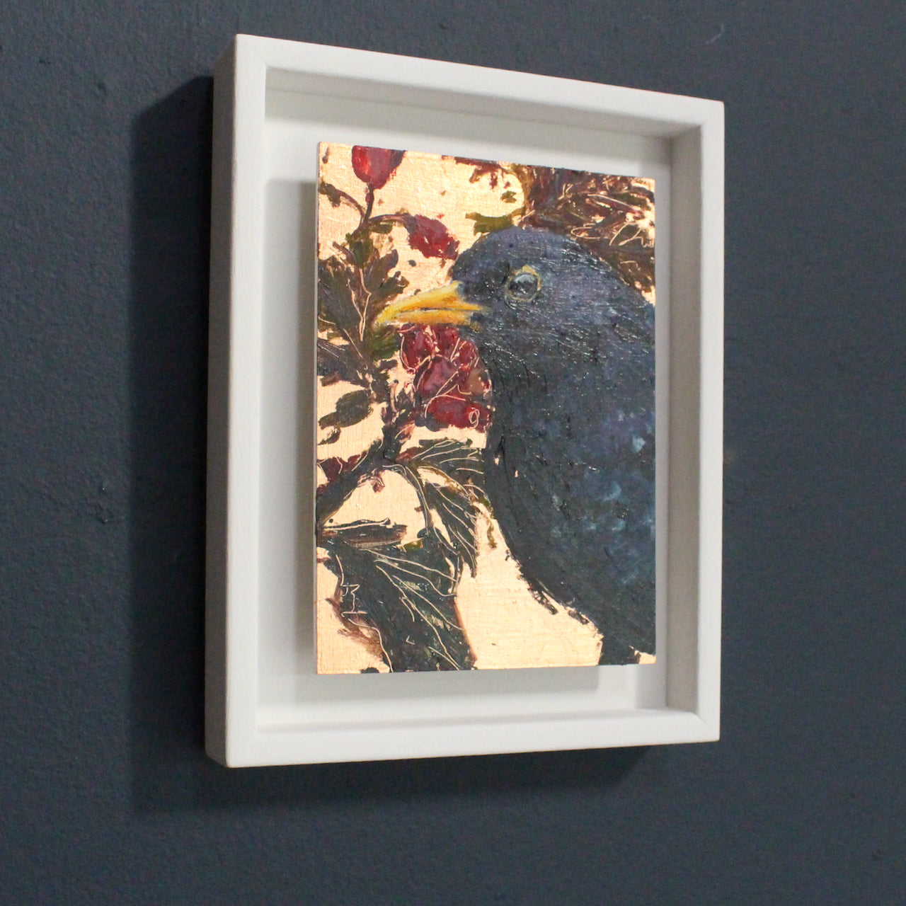framed painting by Jill Hudson of a blackbird on background of gold with red berries and  green leaves